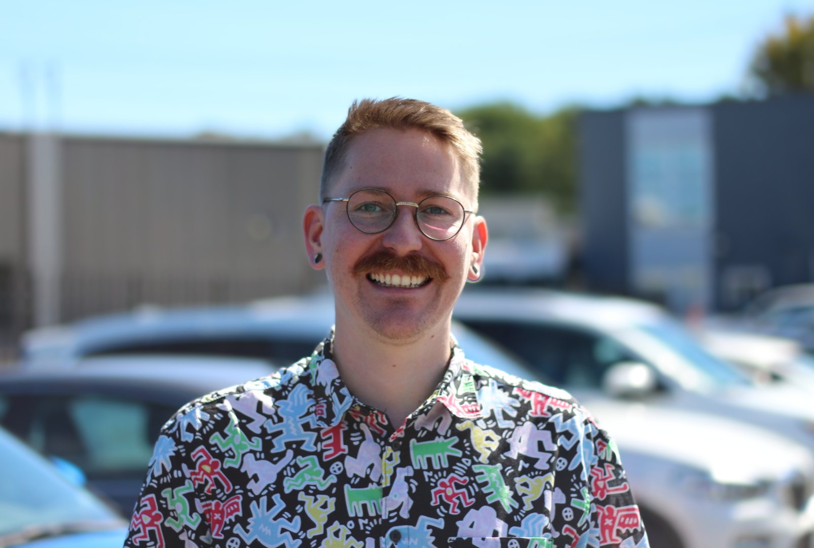 James Murchison smiling outdoors, wearing glasses and a colourful patterned shirt.